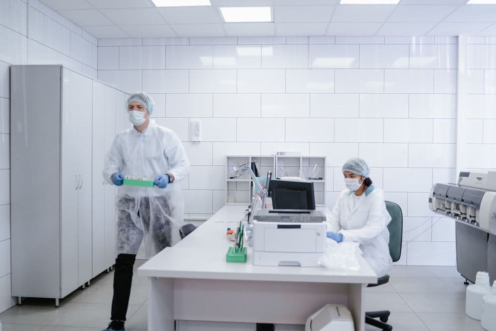 Two researchers in protective clothing working in a bright, clean laboratory